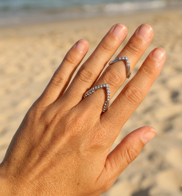 Hand wearing two diamond rings on a beach