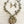 Load image into Gallery viewer, An antique bronze-toned necklace and matching drop earrings featuring textured leaf charms, small round beads, and a large leaf-shaped pendant with cutout details, displayed on a light wood surface.
