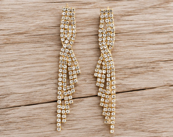Golden cascading crystal earrings on pale barn wood