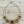 Load image into Gallery viewer, A gold-toned statement necklace featuring five ornate floral elements with dark centers and small clear rhinestones, displayed on a light wood background.
