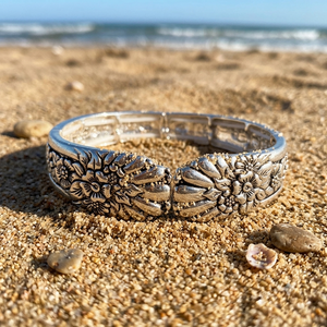 Silver bracelet with floral designs on a sandy beach