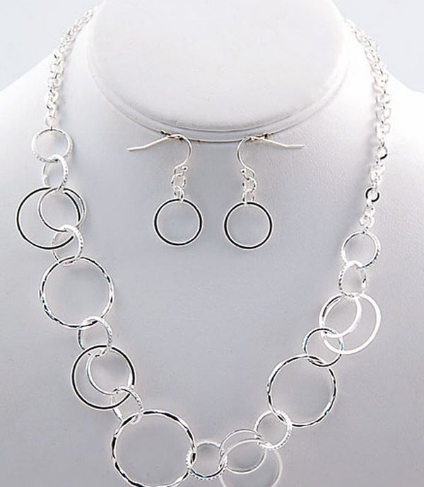 Silver jewelry set featuring a statement necklace and matching drop earrings with interlocking circular links, displayed on a white mannequin bust.