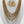 Load image into Gallery viewer, A multi-layered statement necklace set with matching teardrop-shaped dangle earrings, displayed on a white mannequin bust. The necklace features multiple strands of small gold and silver beads, silver chain layers, and a central silver-toned pavé charm.
