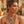 Load image into Gallery viewer, A woman wearing a layered bohemian-style necklace with gold, silver, and white crystal elements, styled with matching gold hoop earrings in a warm, rustic outdoor setting.
