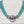 Load image into Gallery viewer, A multi-strand turquoise beaded necklace with a large polished silver-toned central clasp and hanging ring, displayed on a light wood background.
