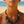Load image into Gallery viewer, A close-up of a model wearing a chunky statement necklace with a leopard print bib design and beaded strands, set against a blurred beach background.

