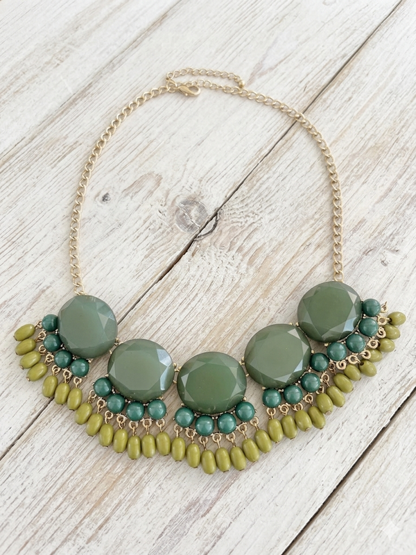 Necklace with green and gold beads on a wooden surface