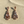 Load image into Gallery viewer, Pair of ornate earrings on a sandy surface
