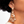 Load image into Gallery viewer, Close-up of a person wearing a rose gold earring with clear gemstones.
