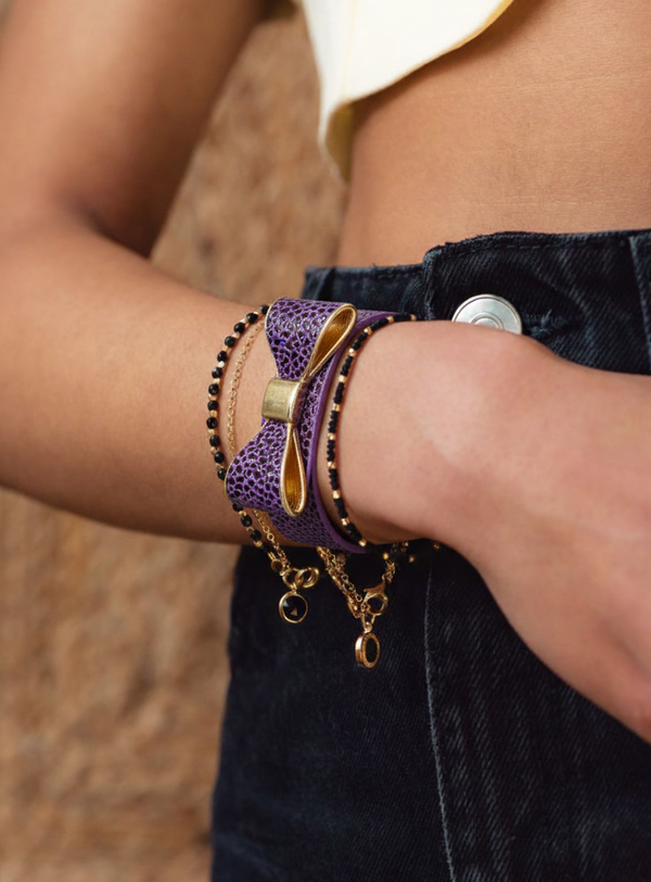 Close-up of a person's wrist wearing multiple bracelets with a blurred background