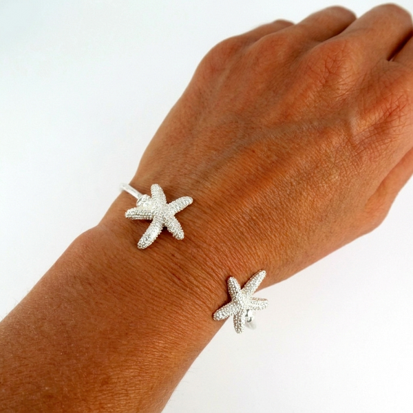 Silver starfish bracelet on a wrist against a white background