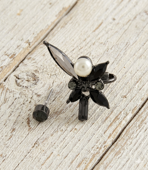 Black and pearl earring on a wooden surface