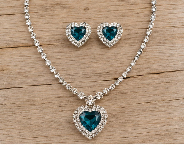 Teal heart necklace and clip-on earrings on pale barn wood