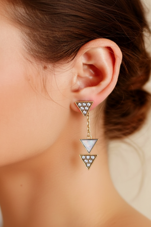 Triangle-shaped earrings with gemstones worn by a person