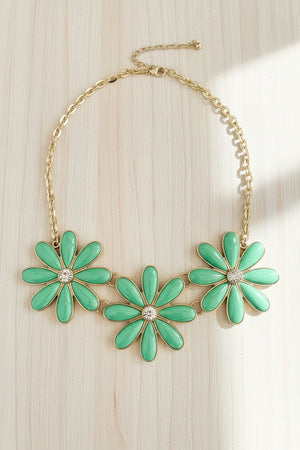 Necklace with green flower-shaped pendants on a dark surface
