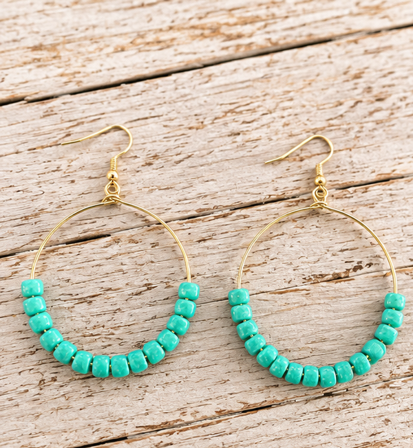 Turquoise beaded gold-tone hoop drop earrings on pale barn wood, 2.75 inches