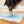Load image into Gallery viewer, A pet food mat with an abstract blue line design, featuring the brand name 'Uniklook', placed on a wooden floor with a dog eating from a bowl on top of the mat.
