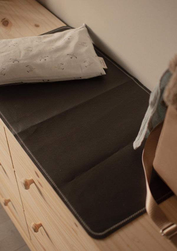Person folding a piece of fabric on a wooden surface