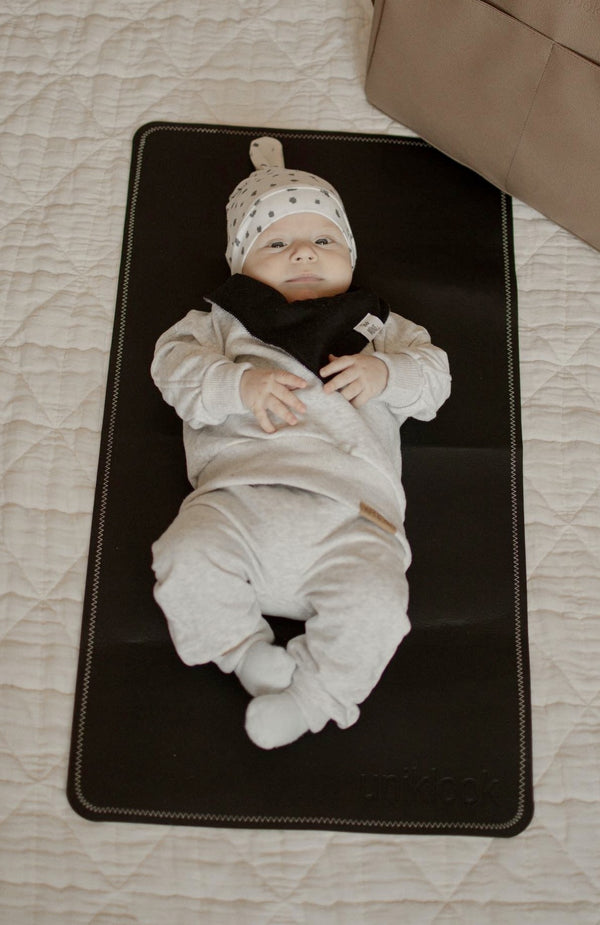 Baby lying on a black mat with a neutral background