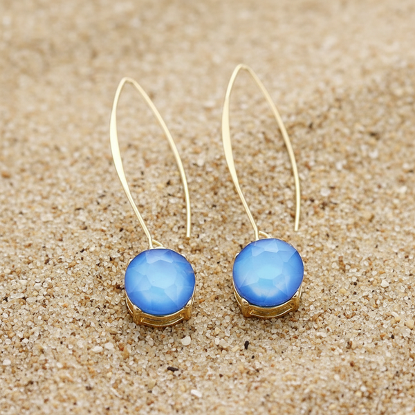 Gold earrings with blue gemstones on a wooden surface