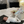 Load image into Gallery viewer, Baby lying on a black mat with a basket of items on a bed.
