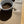 Load image into Gallery viewer, A tan pet bowl mat with a gray border, placed on a wooden floor, with a bowl of pet food and a dish with water on top of it placed on the mat.
