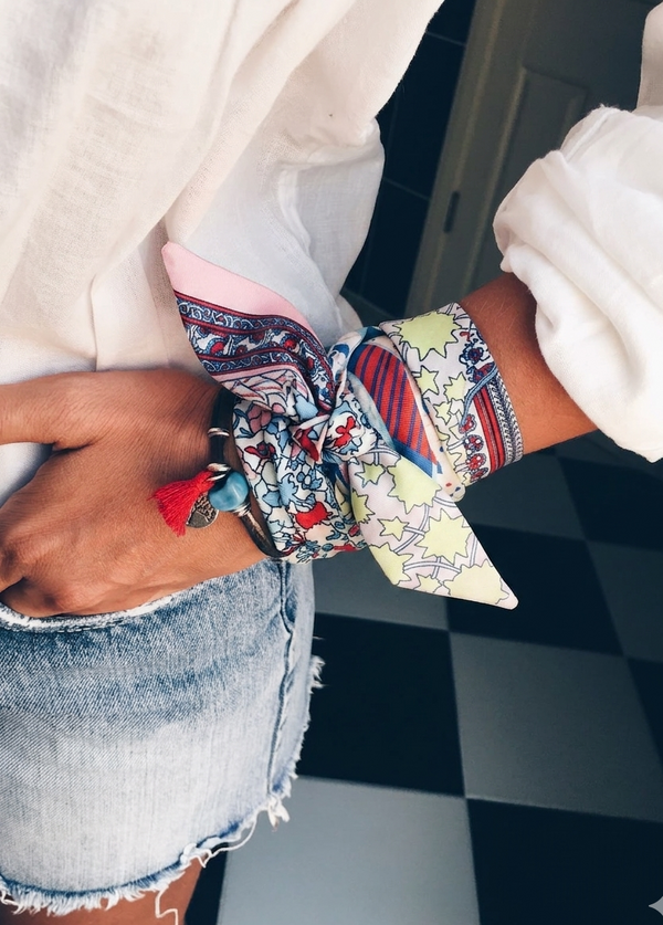 Person wearing colorful patterned wristbands on a checkered floor