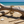Load image into Gallery viewer, Gold chain bracelet on a piece of driftwood with a beach background
