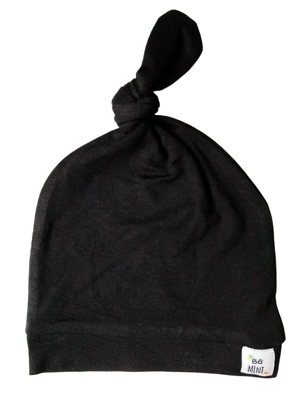 A black knot hat for babies with an adjustable knot at the top, made from stretchy fabric.