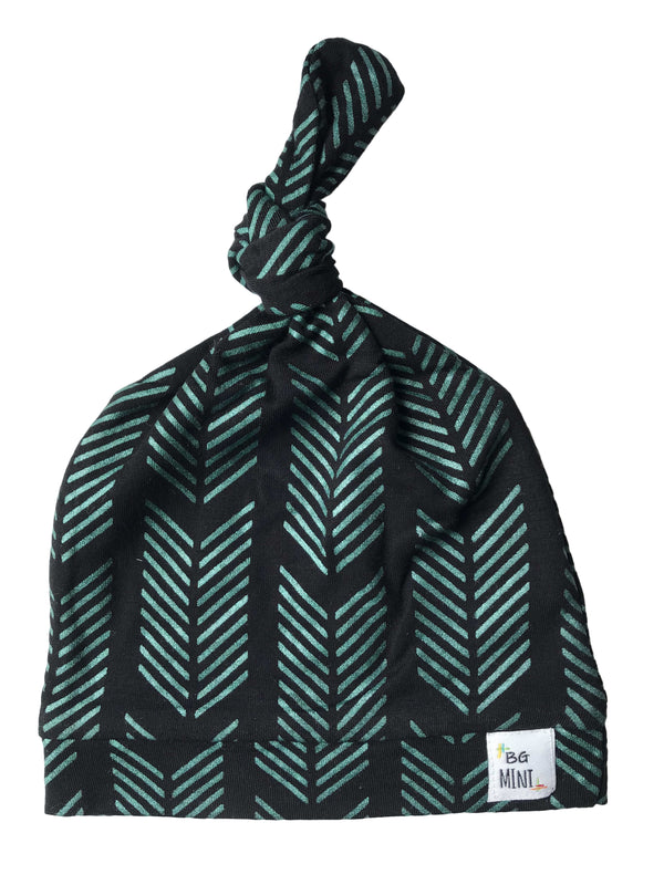 A black and green geometric patterned knot hat for babies